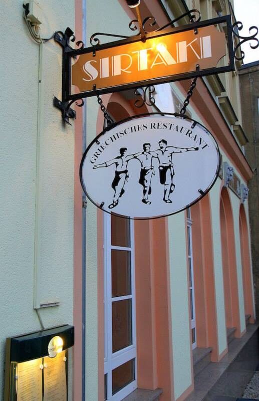 Beleuchtetes Sirtaki-Schild mit Tänzer-Logo an der Fassade