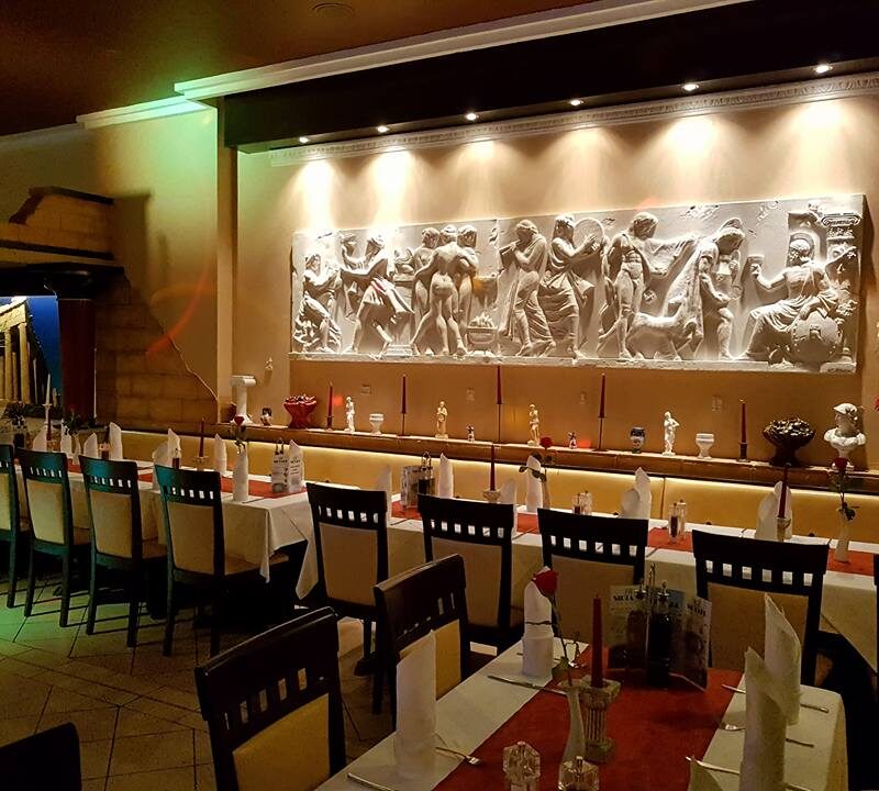 Gastraum mit langer Tafel vor dem beleuchteten Marmorrelief